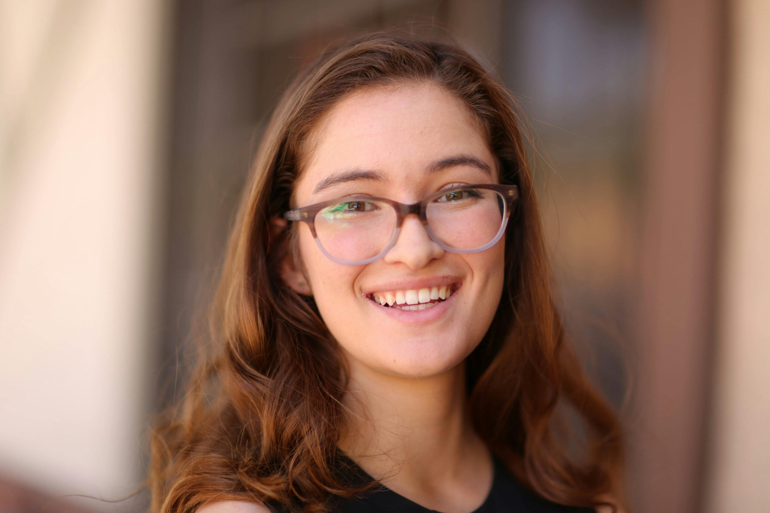 Happy young woman in glasses smiling warmly in this close-up portrait.