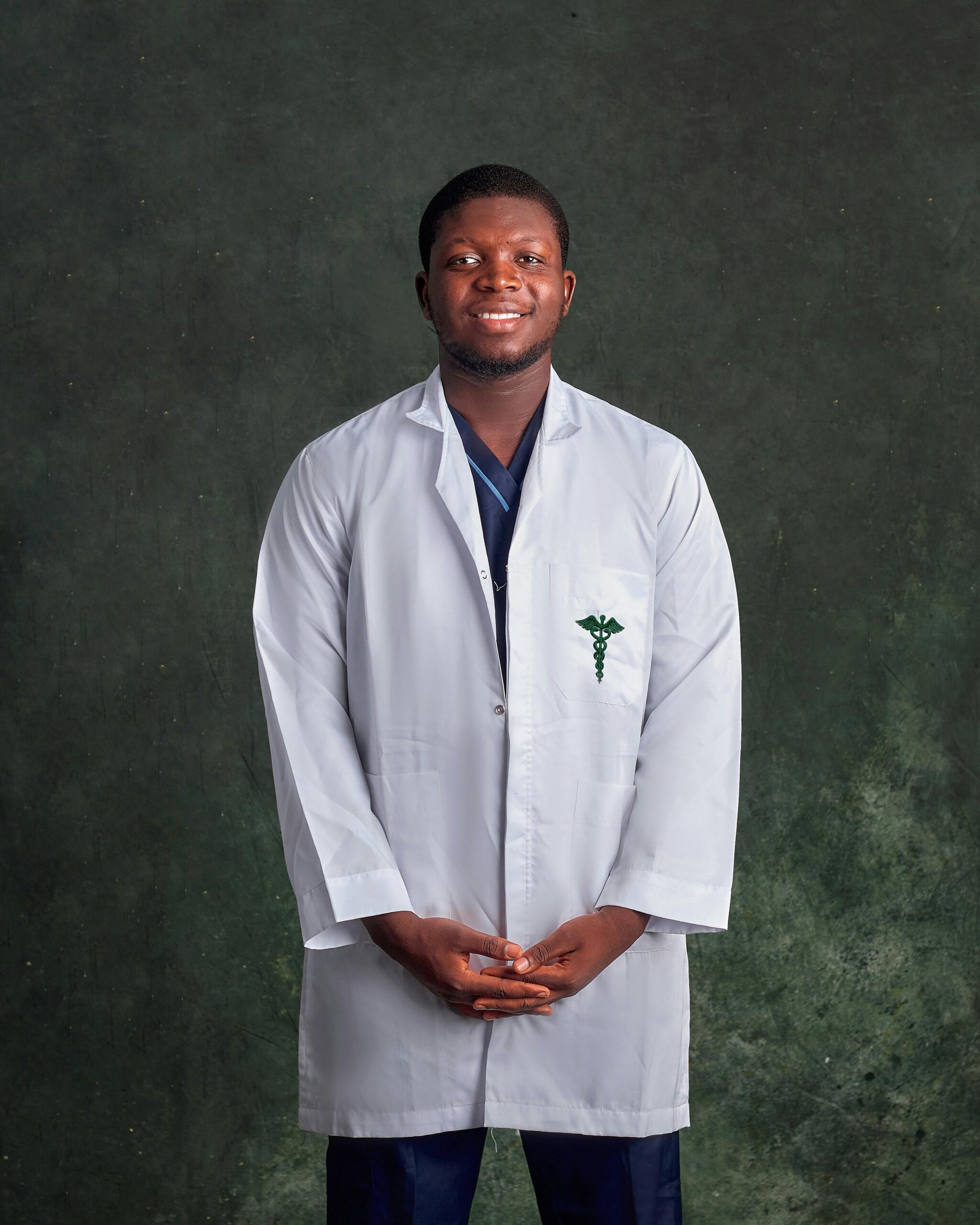 Confident male doctor in white coat smiling against green background.